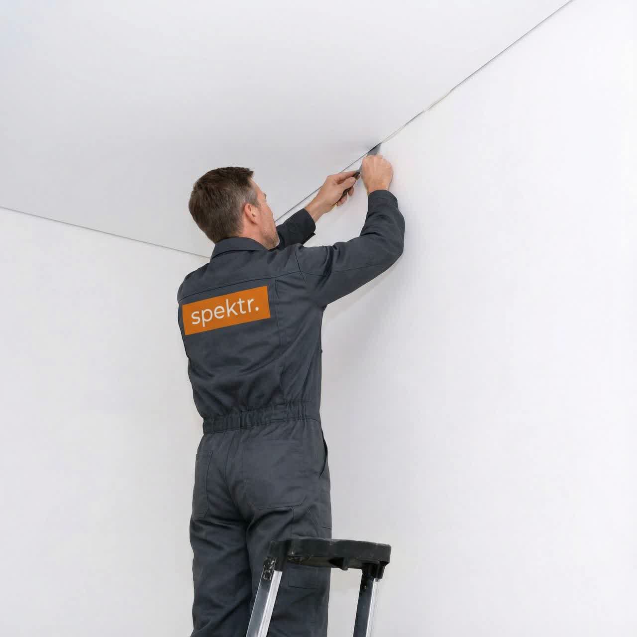 Монтажник устанавливает натяжной потолок